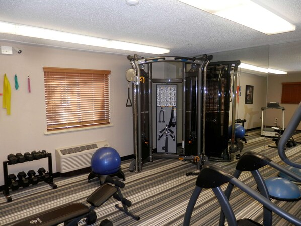 Un gimnasio con equipamiento de ejercicio, una bicicleta vertical y una cinta de correr.
