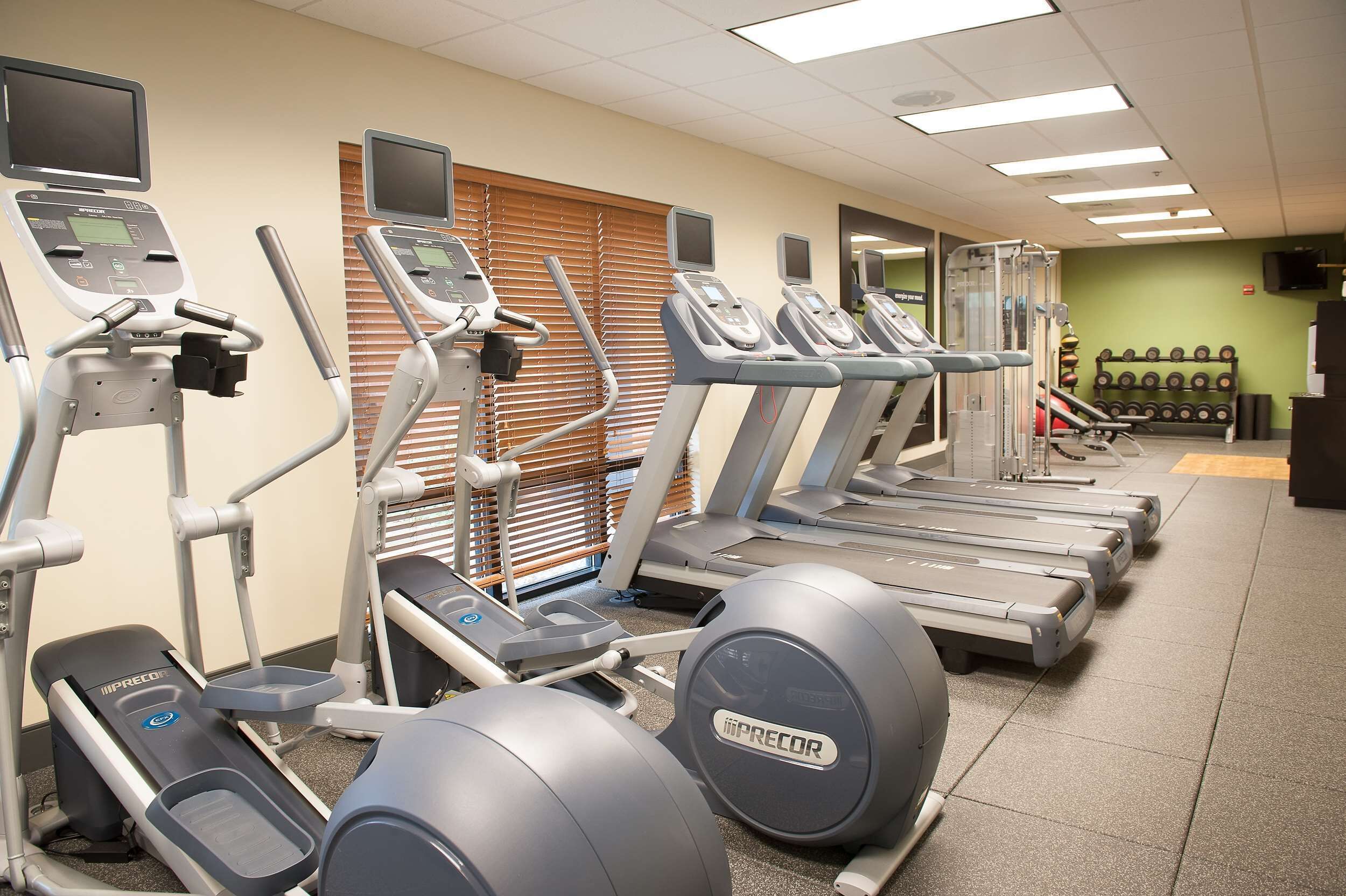 A gym with treadmills, elliptical machines, and weightlifting equipment.
