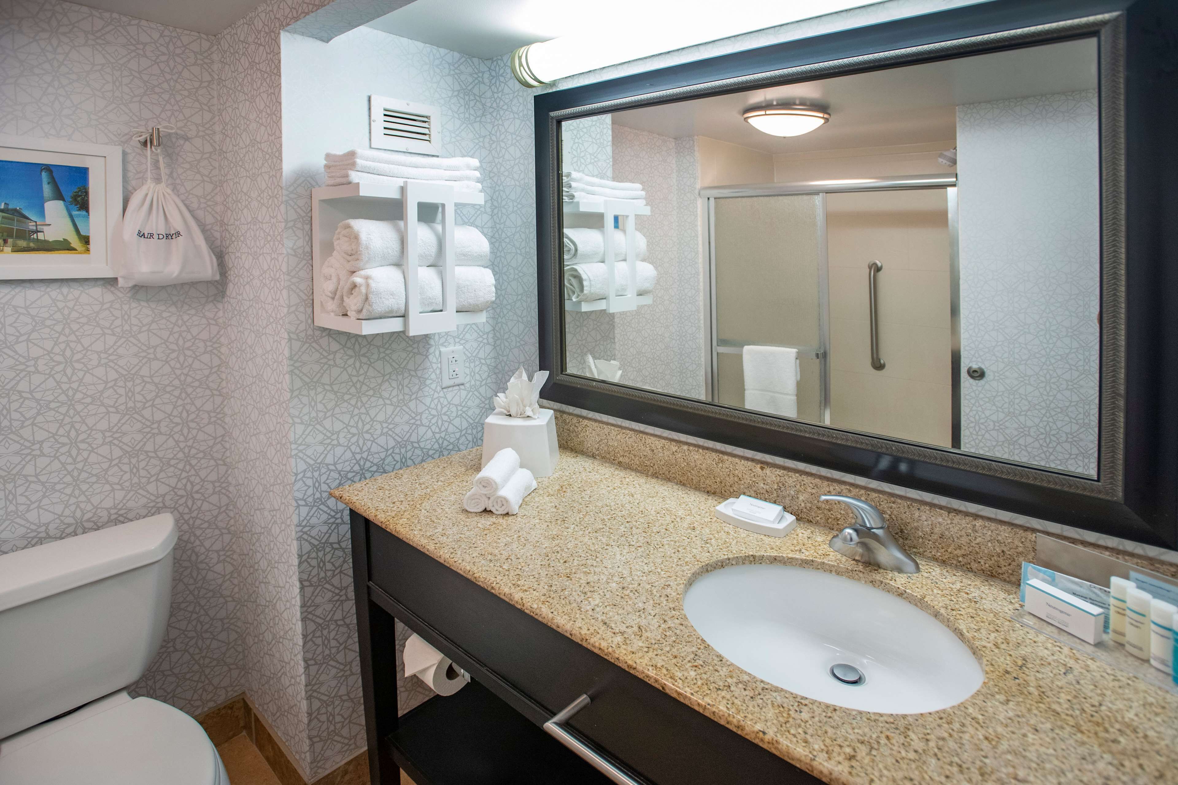Une salle de bain équipée d’un lavabo, d’un miroir, d’un porte-serviettes et de toilettes.
