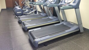 A row of treadmills in a gym with a tiled floor and a window with blinds. - Hampton Inn Pensacola-Airport (Cordova Mall Area) (Pensacola)