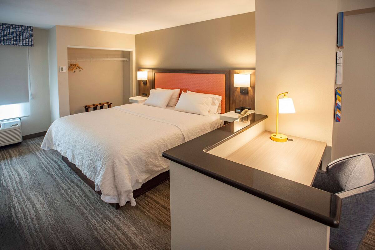 A hotel room with a large bed, bedside tables, a desk, and a chair.