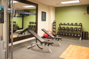 A gym with benches, dumbbells, and a red exercise ball.
