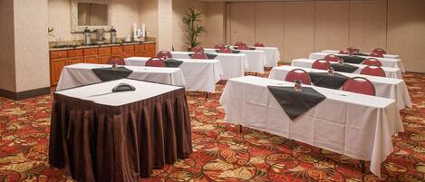 A conference room with tables set up for meetings, a buffet area, and a large mirror on the wall.