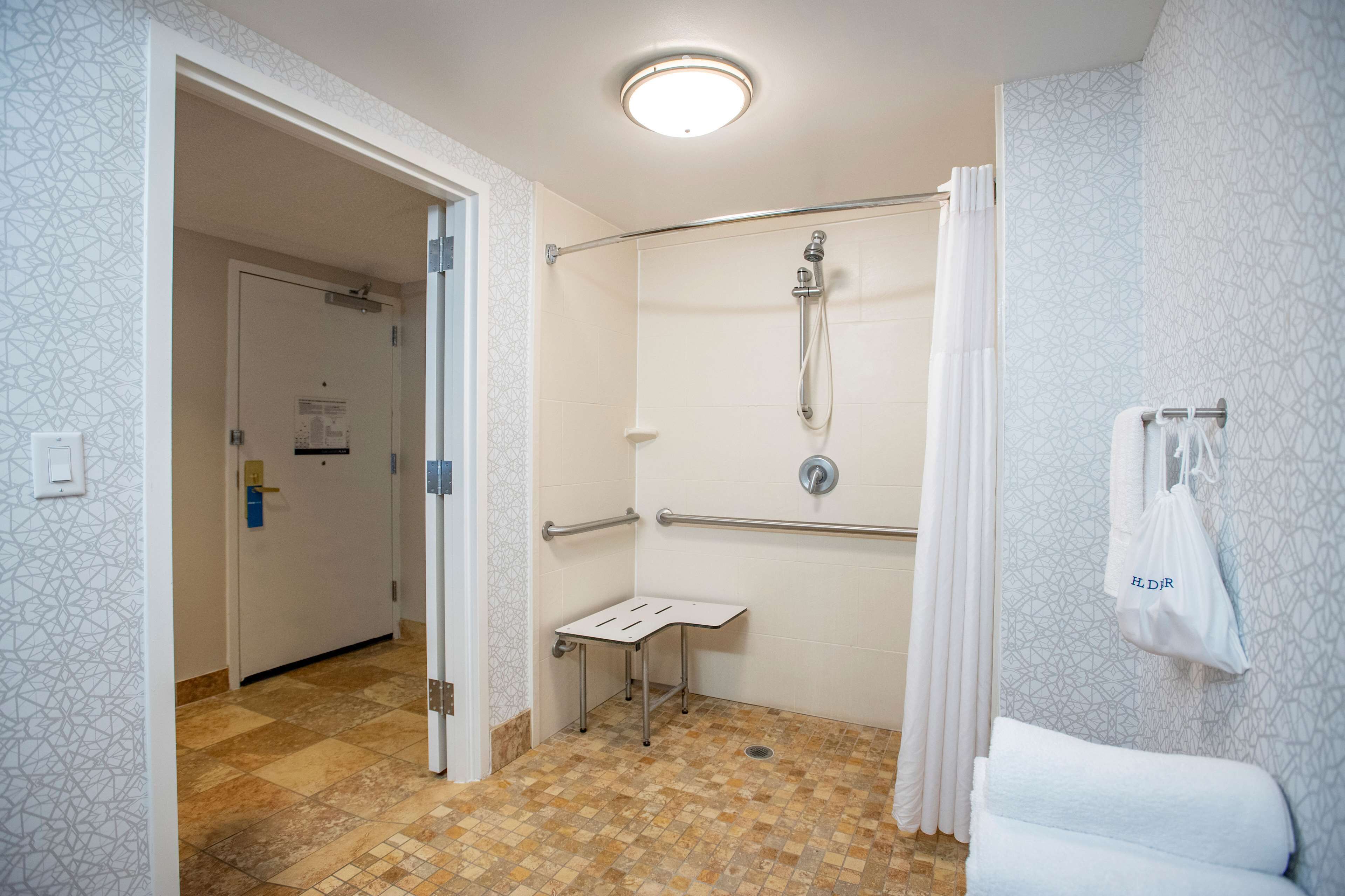 A modern bathroom with a shower, grab bar, and towel rack.