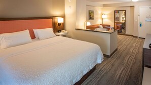 A hotel room with a large bed, a desk, a chair, and a door. - Hampton Inn Pensacola-Airport (Cordova Mall Area) (Pensacola)