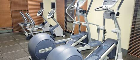 Une salle de sport équipée de tapis de course, d’elliptiques et de vélos d’appartement.