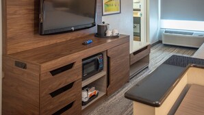 A modern room with a flat-screen TV mounted on a wooden cabinet, a microwave, and a small shelf with a coffee maker. - Hampton Inn Pensacola-Airport (Cordova Mall Area) (Pensacola)