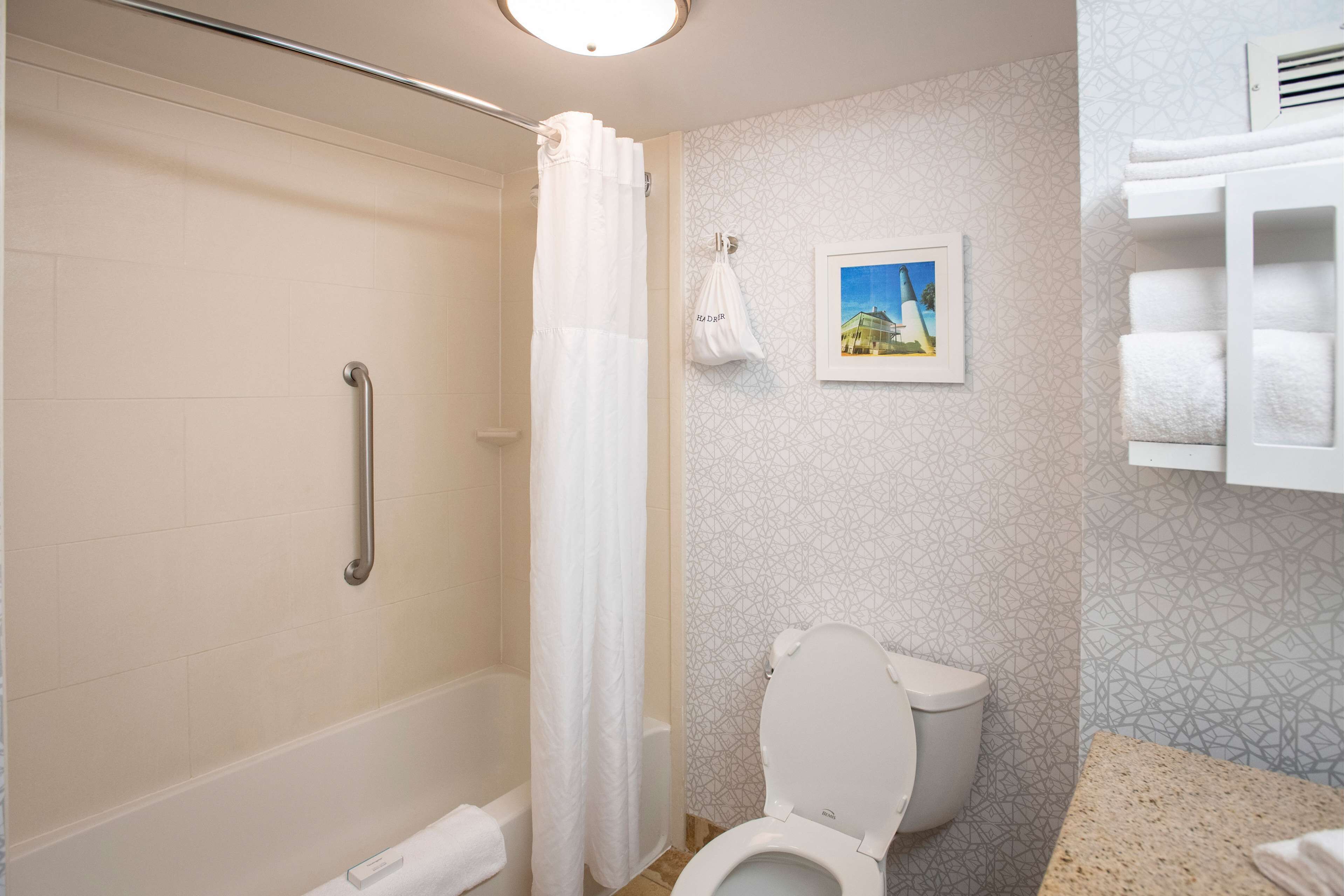 A bathroom with a shower, toilet, and a towel rack.