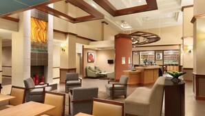 A hotel lobby with seating areas, a fireplace, a bar, and a dining area. - Hyatt Place Denver South/Park Meadows (Lone Tree)