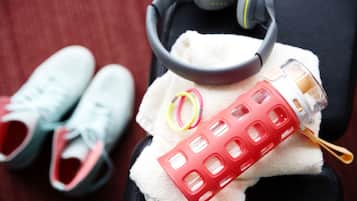 A pair of sneakers, a pair of headphones, and a water bottle on a towel.