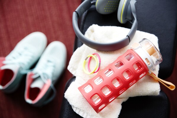 Zapatillas deportivas, auriculares y una botella de agua sobre una toalla.