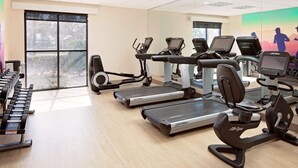 Et fitnesscenter med løbebånd, crosstrainere og håndvægte.