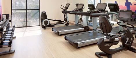 Un gimnasio con cintas de correr, elípticas y mancuernas.