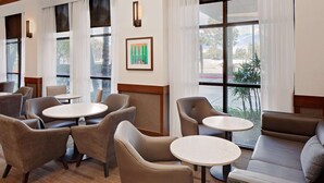 Et hotel lobby med siddepladser, herunder sofaer og stole, samt et stort vindue med udsigt til det fri.