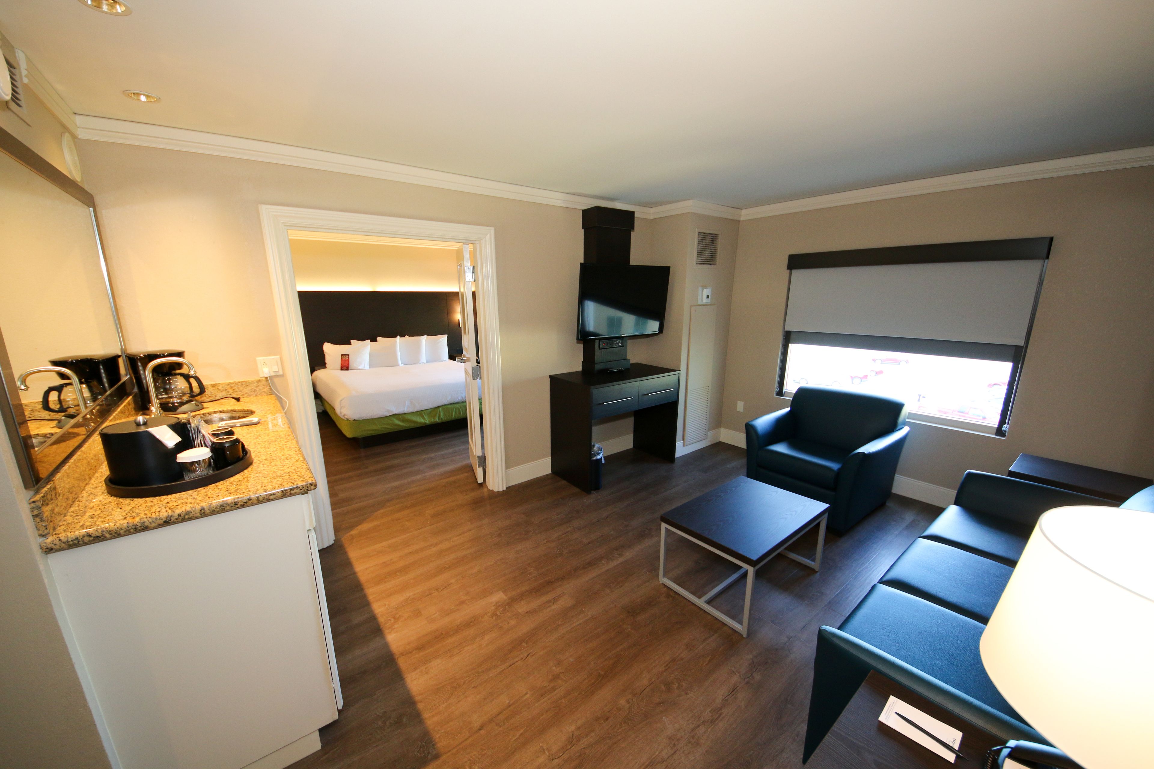 Habitación de hotel con cama, televisión, cafetera, escritorio y una silla.