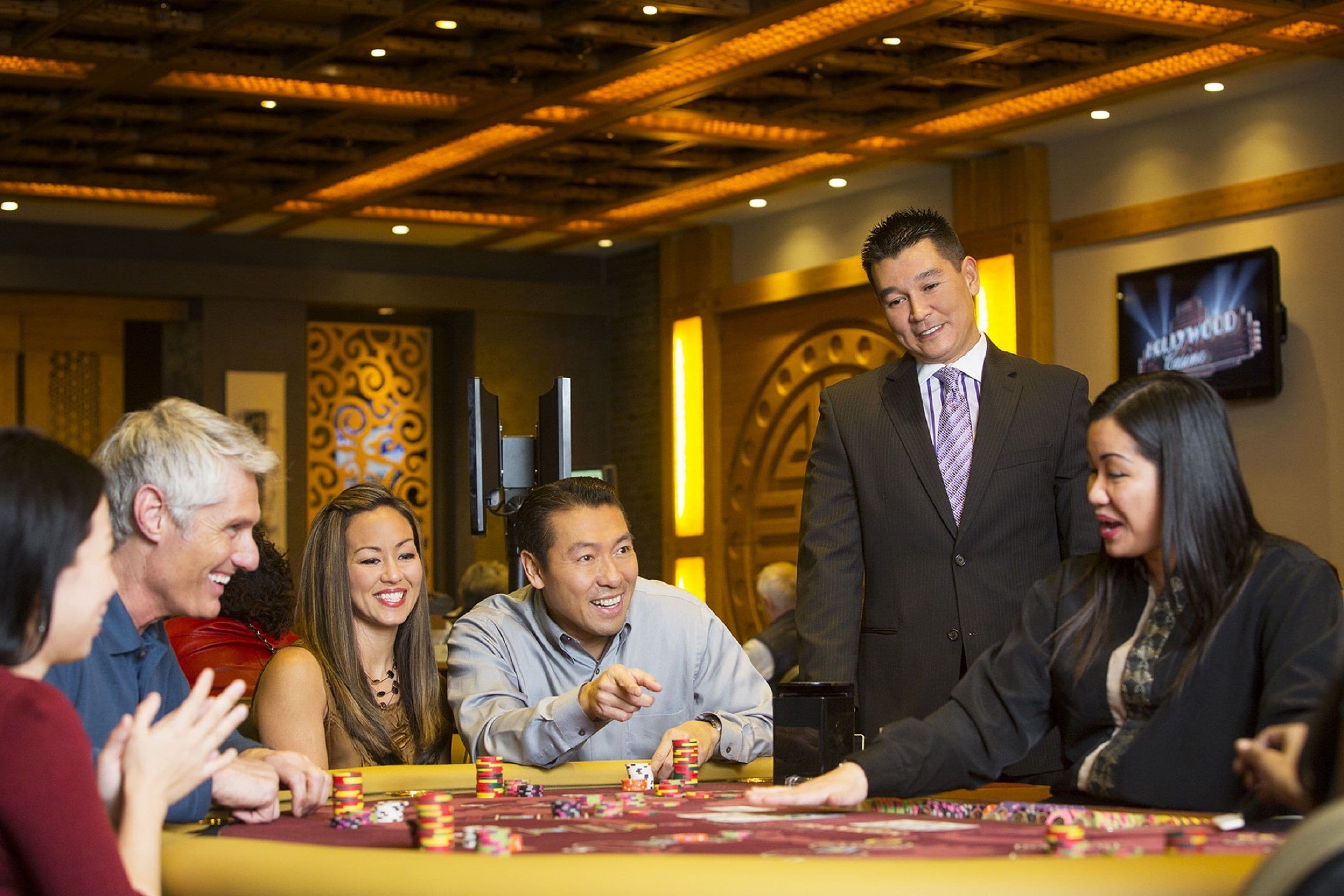 Un grupo de personas jugando cartas en una mesa de casino con fichas.