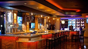 Una zona de bar con una barra larga, múltiples pantallas y asientos.