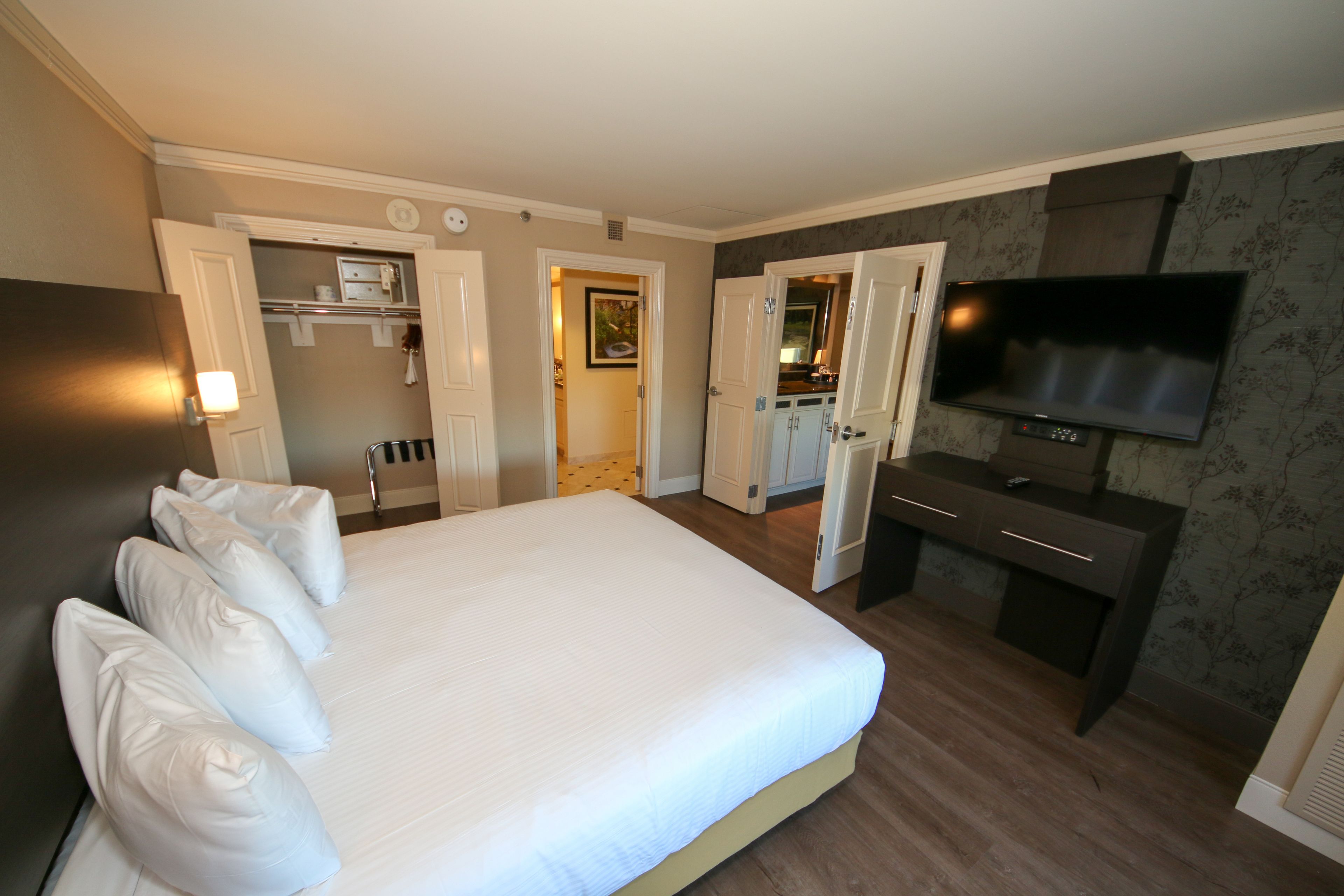 Une chambre d’hôtel avec un grand lit, une télévision, un bureau et un dressing.