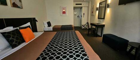 Una habitación de hotel con una cama grande, un escritorio, una silla y una mesita.