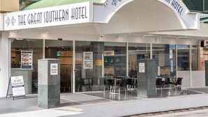 The exterior of The Great Southern Hotel with a clear sign, a glass facade, and outdoor seating area. - Great Southern Hotel Brisbane (Brisbane)