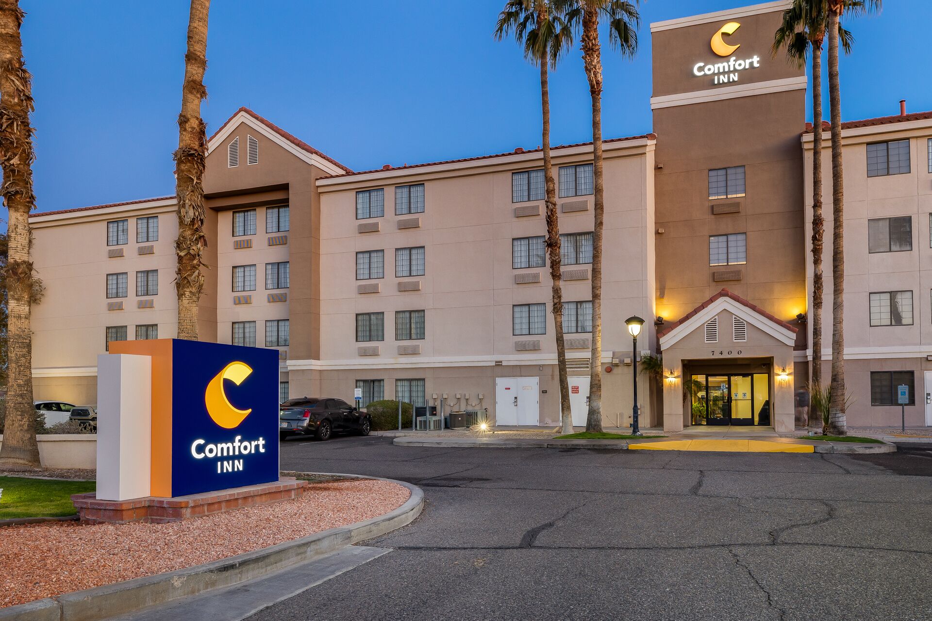 A Comfort Inn hotel with a large sign, multiple floors, and a parking area.