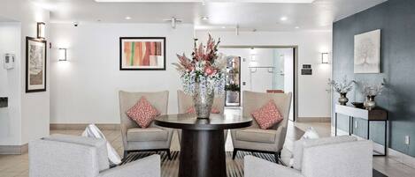 A modern lobby with a round table, grey sofas, and a chandelier.