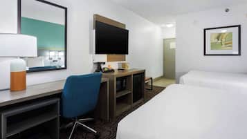 A hotel room with a bed, a desk with a chair, a television, and a framed picture on the wall.