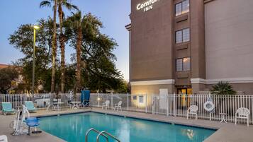 Una piscina al aire libre, sombrillas, sillones reclinables de piscina
