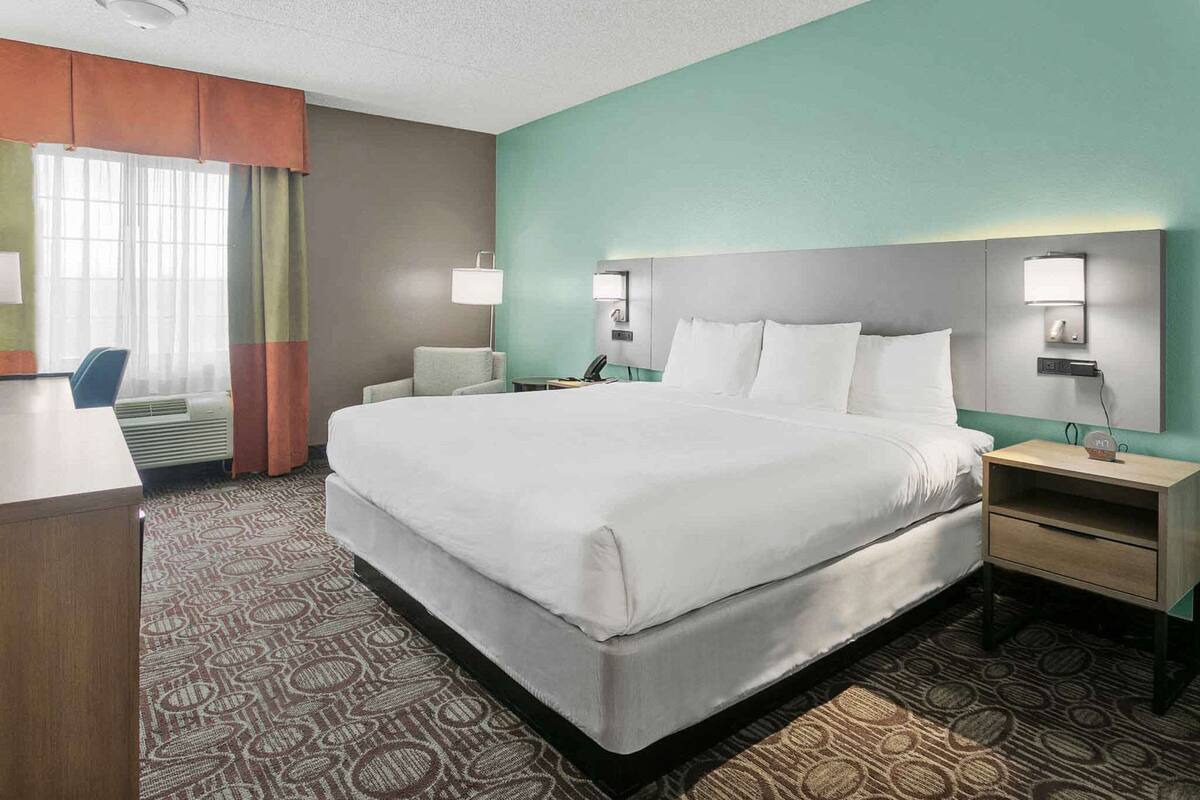 A hotel room with a large bed, two bedside tables, a desk, and a chair.