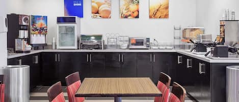 A restaurant with a counter, seating area, and kitchen equipment.