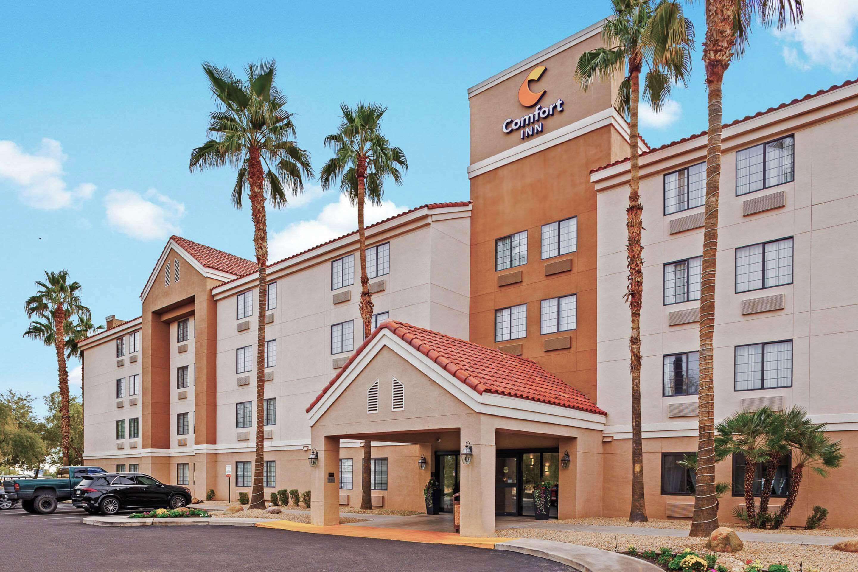 Een Comfort Inn hotel met een rode pannendak, meerdere verdiepingen en palmbomen.