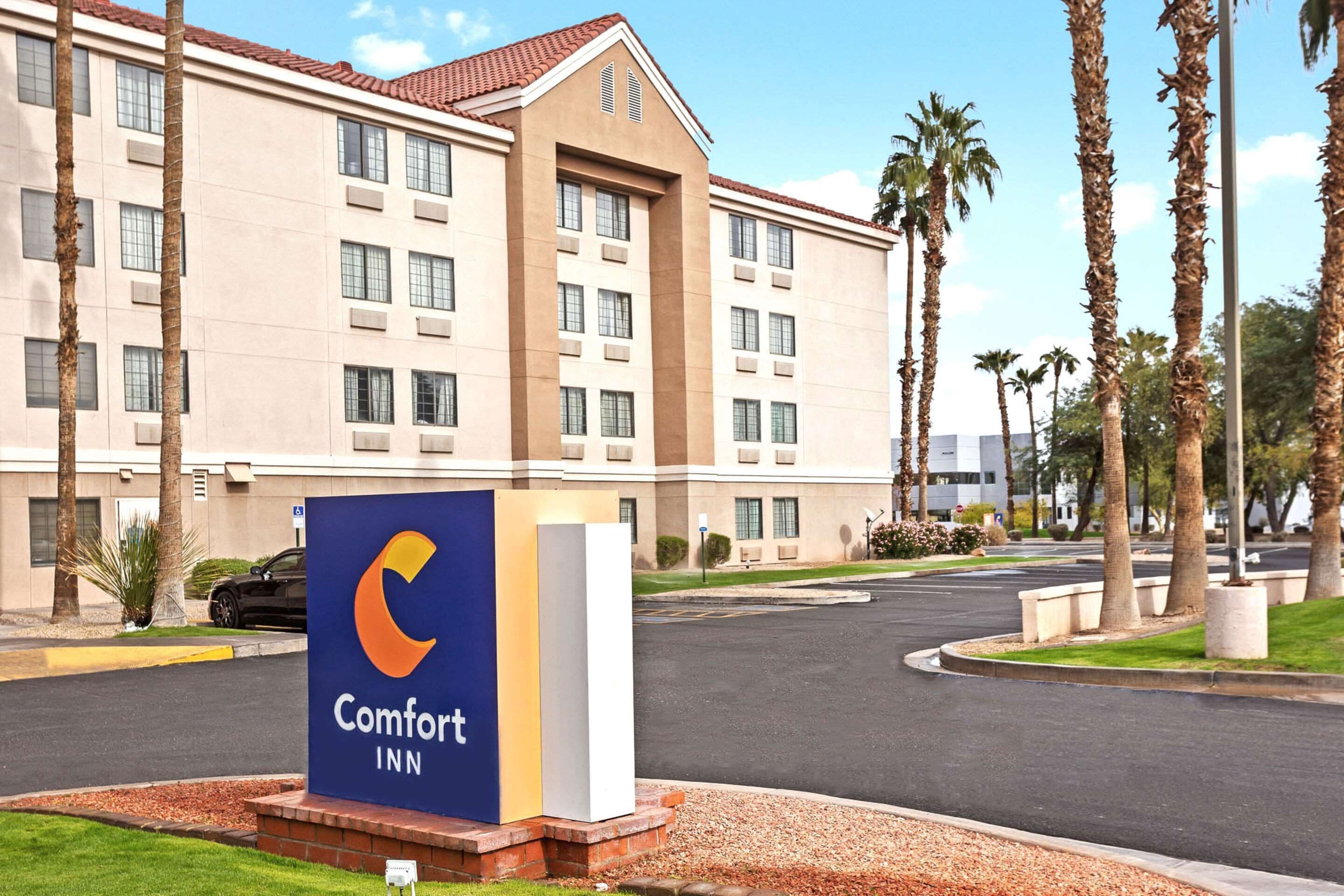 Un hôtel Comfort Inn avec une enseigne bien visible, un parking et des palmiers en arrière-plan.