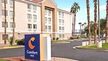 Un hôtel Comfort Inn avec une enseigne bien visible, un parking et des palmiers en arrière-plan.
