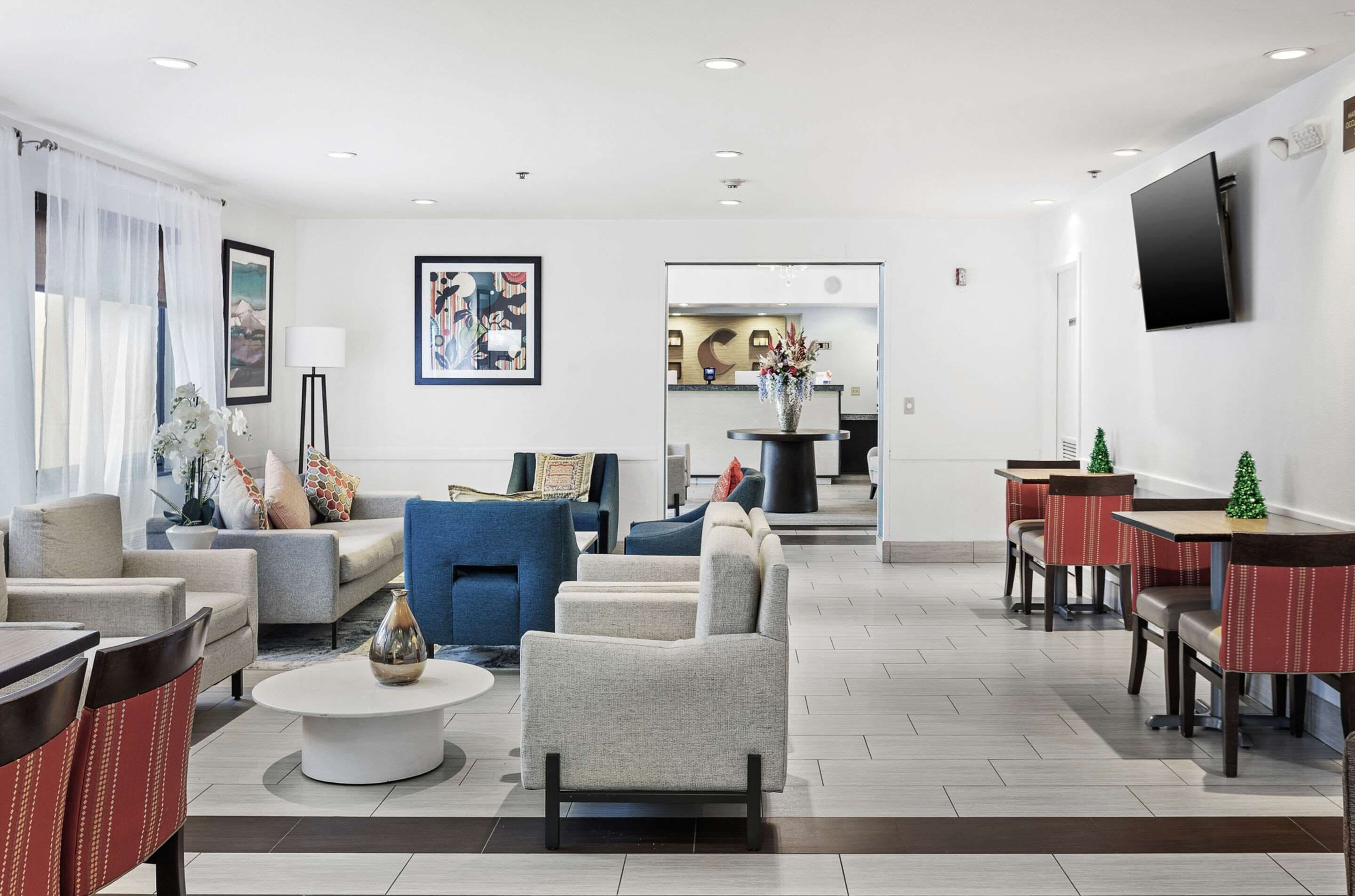 Een moderne hotelentree met een zithoek, een receptiebalie en een eetgedeelte.
