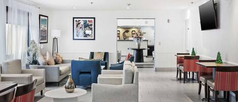Een moderne hotelentree met een zithoek, een receptiebalie en een eetgedeelte.