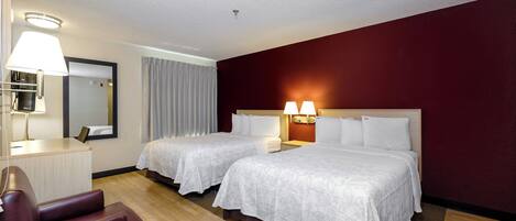 Habitación de hotel con dos camas, un escritorio, una silla y un espejo.