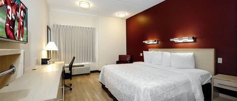 Habitación de hotel con cama, escritorio, silla y un cuadro en la pared.