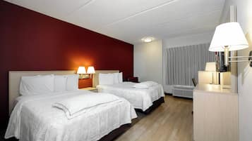 Ein Hotelzimmer mit zwei Betten, einem Schreibtisch und einer Lampe.