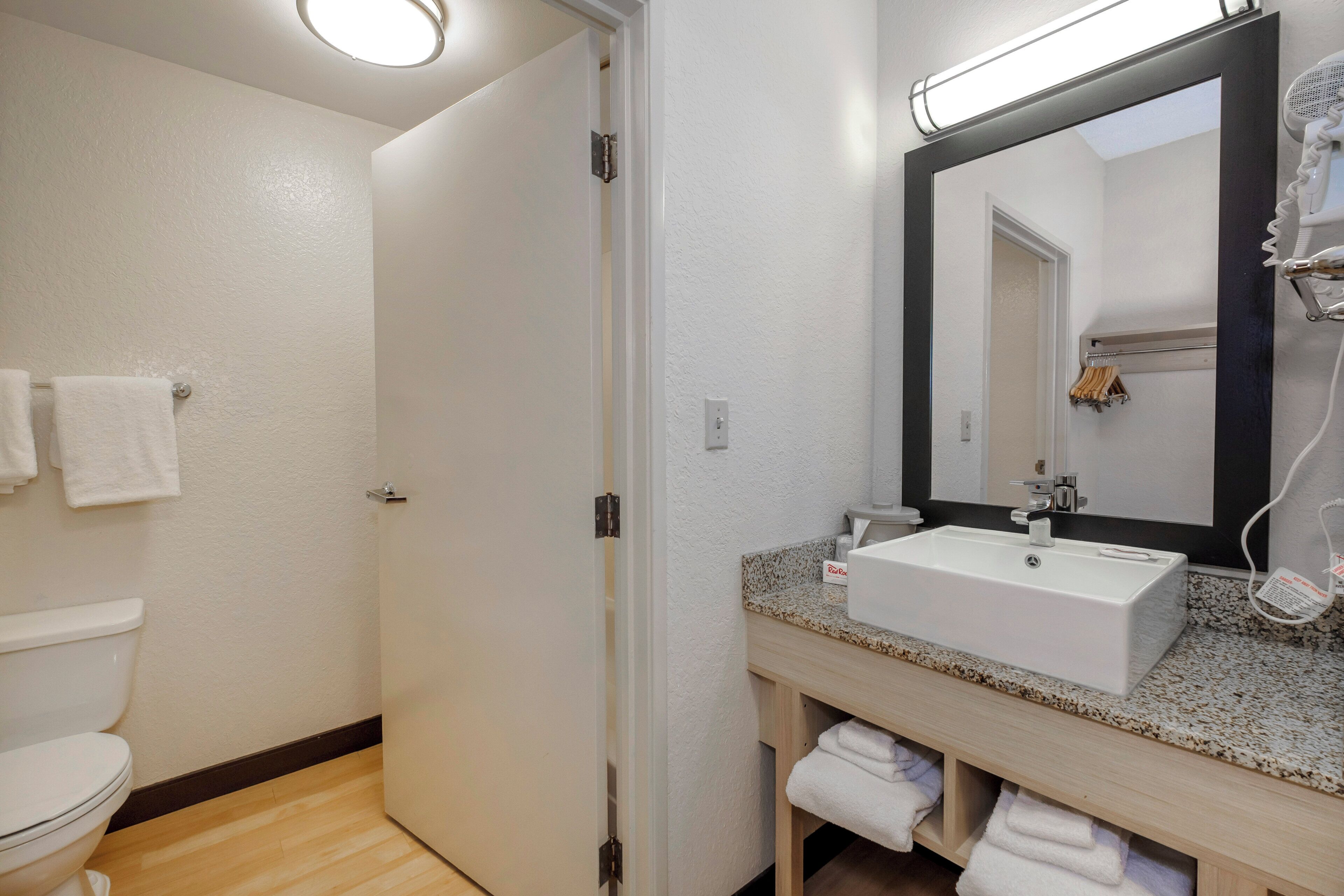 A bathroom with a white sink, a mirror, and a towel rack.