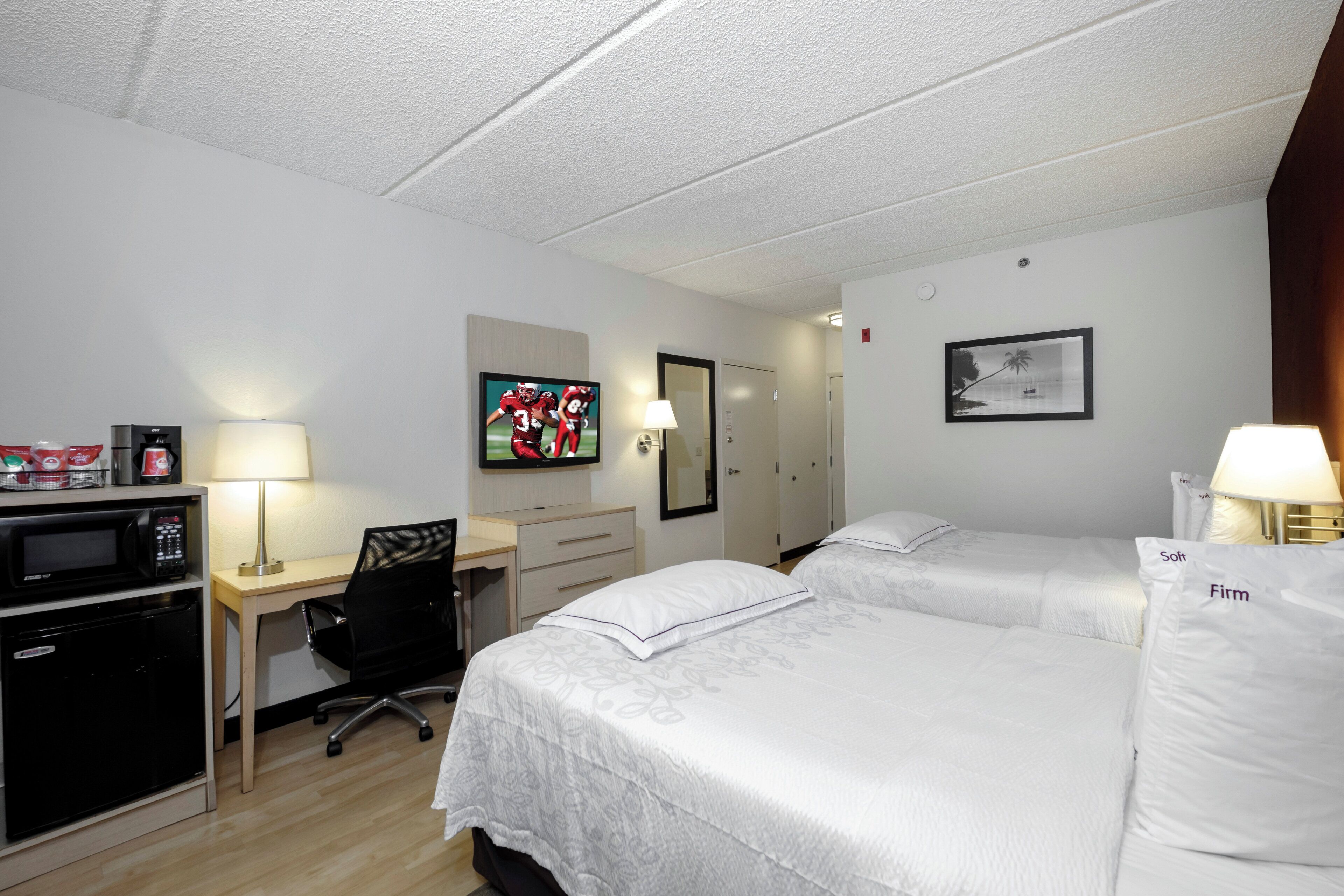 A hotel room with a desk, a television, a bed, and a wardrobe.