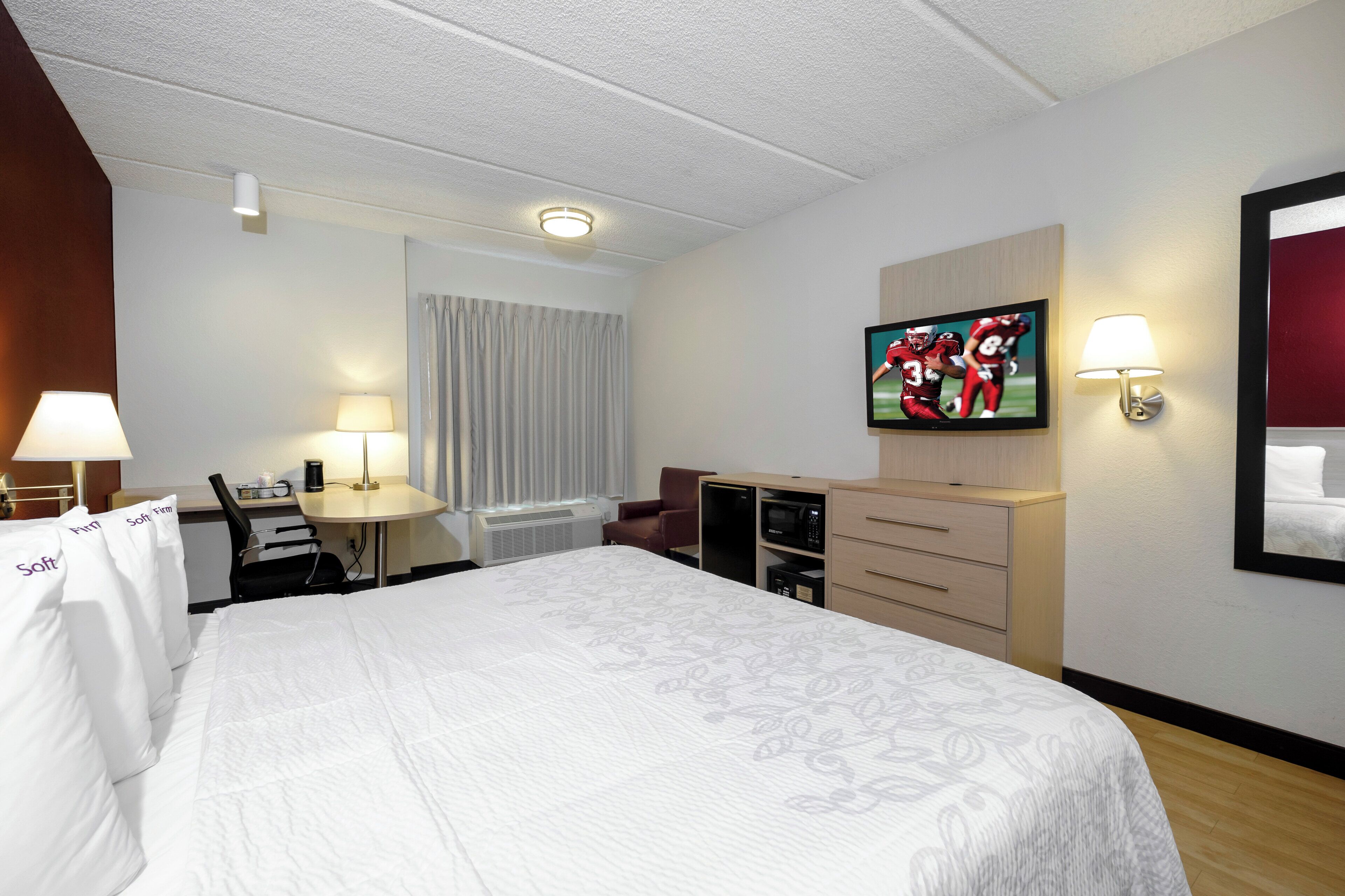 A hotel room with a bed, a desk, a television, and a minibar.