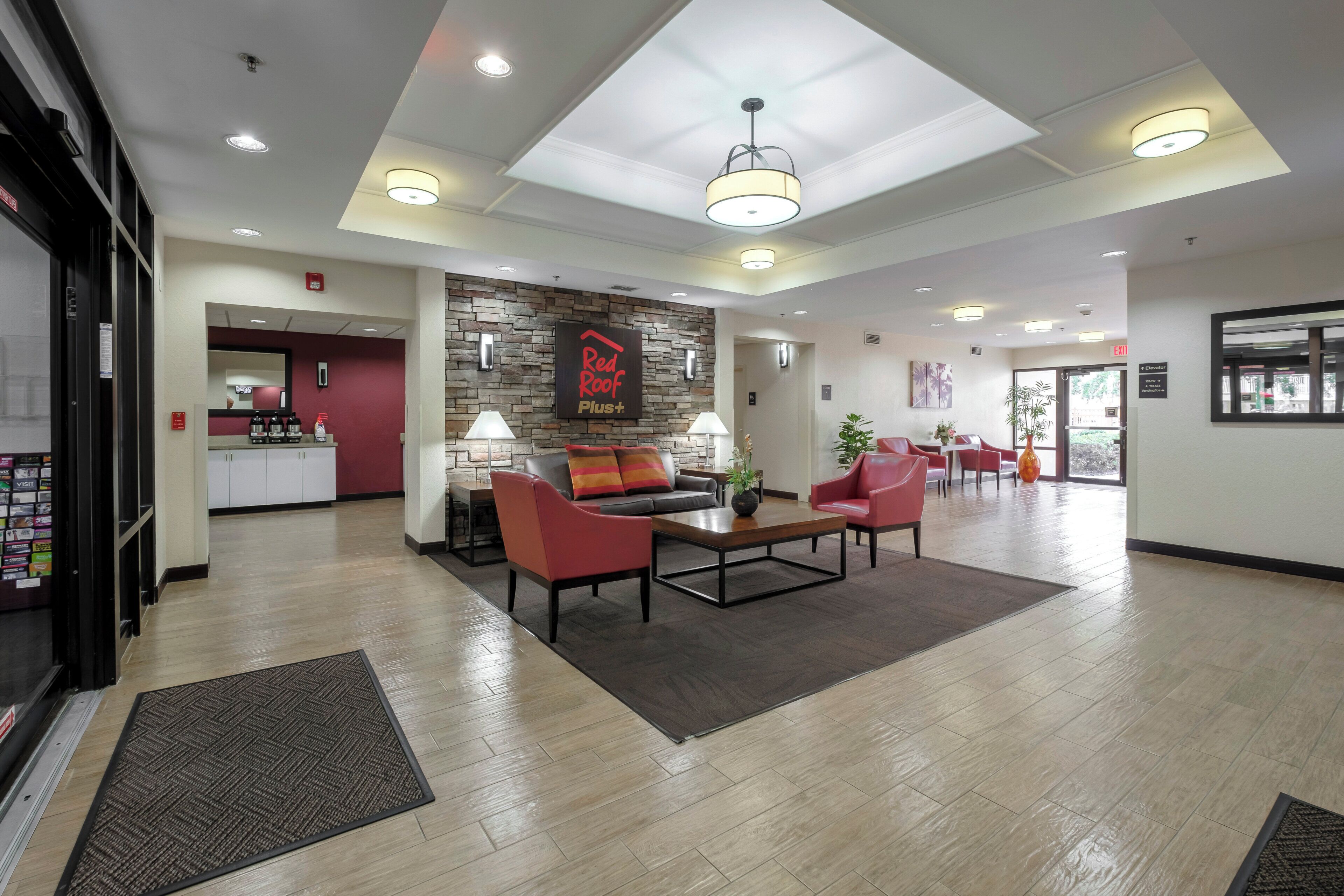 A hotel lobby with a reception desk, seating area, and a staircase leading to the upper floors.