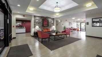 A hotel lobby with a reception desk, seating area, and a staircase leading to the upper floors.