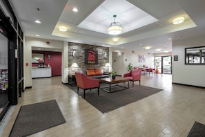 A hotel lobby with a reception desk, seating area, and a staircase leading to the upper floors. - Red Roof Inn PLUS+ Gainesville (Gainesville)