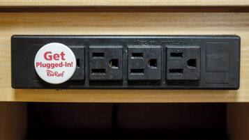 A power strip with a 'Get Plugged-In!' badge and four electrical outlets.