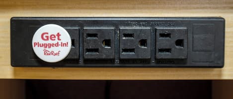 A power strip with a 'Get Plugged-In!' badge and four electrical outlets.