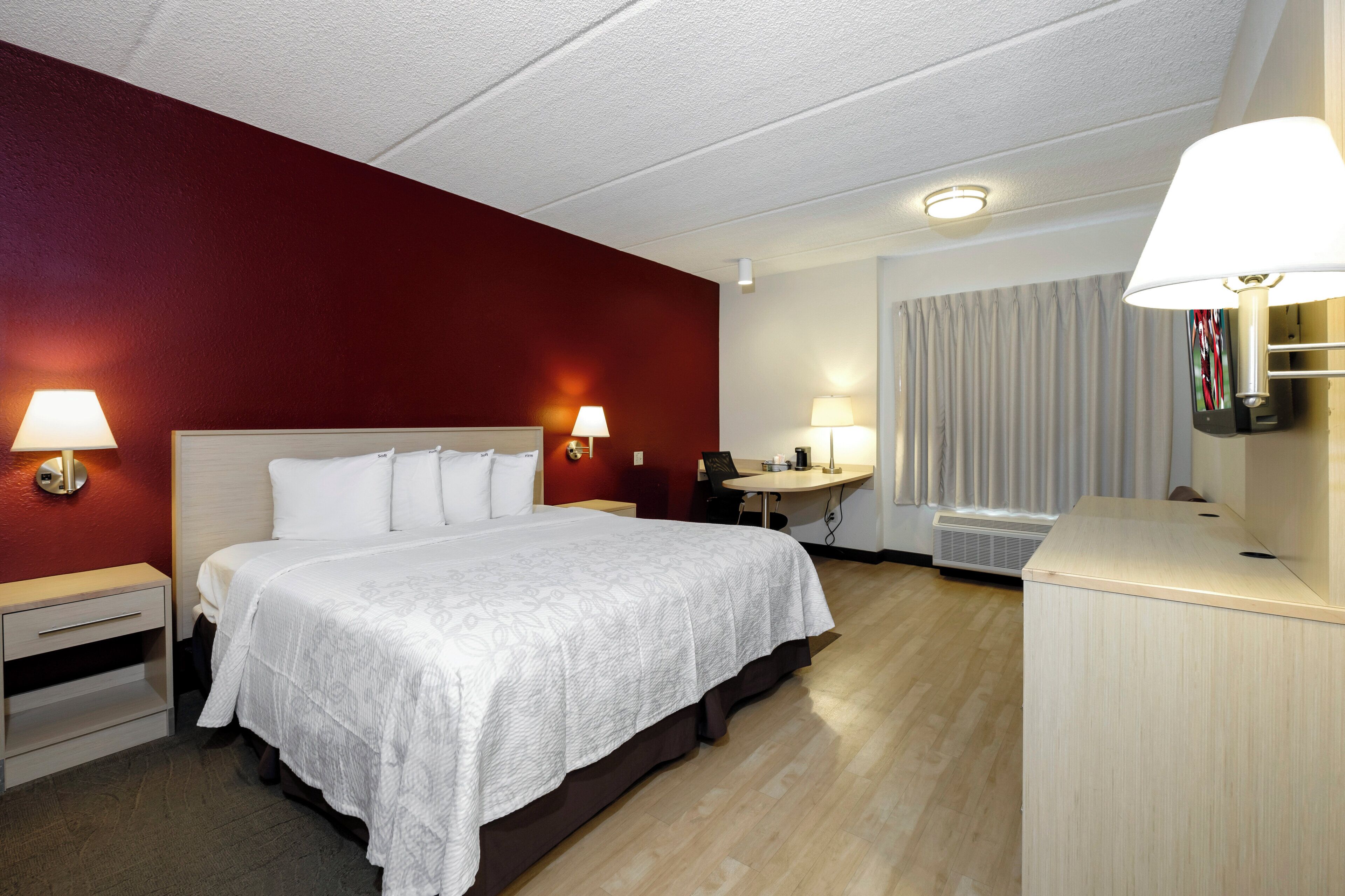 Ein Hotelzimmer mit Bett, Nachttischen, Lampen, einem Schreibtisch und einem Spiegel.