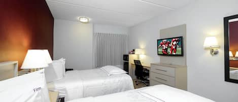 A hotel room with two beds, a desk, a chair, a television, and a mirror.