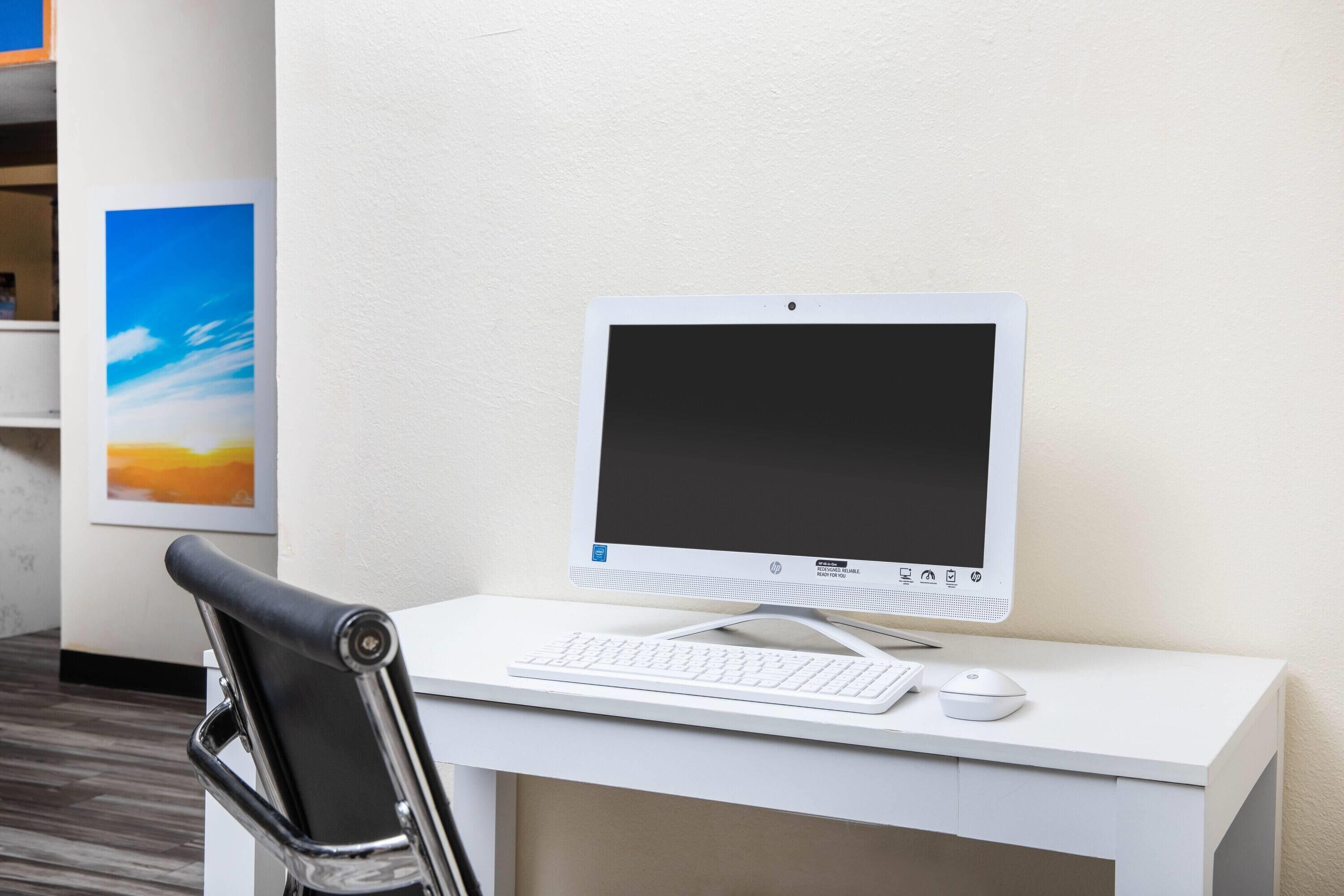 Ein weißer Schreibtisch mit Computer, Tastatur und Maus.