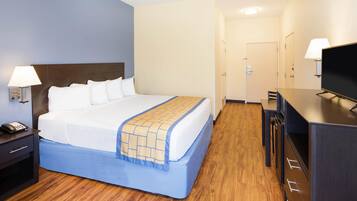 Een hotelkamer met een bed, nachtlampjes, een bureau en een televisie.